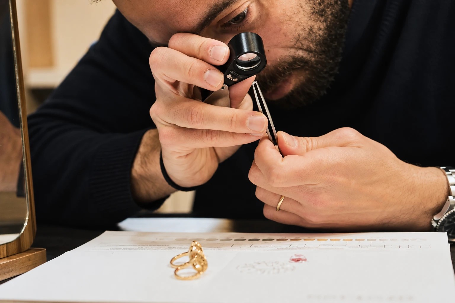 Ruben Caviglia esamina un anello con lente da gemmologo e pinzette